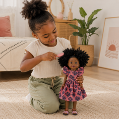 Petite fille qui brosse les cheveux crépus de sa poupée noire Little Happy